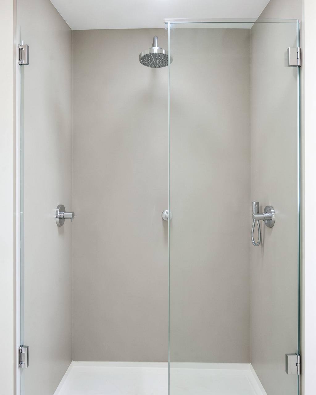 Bright shower with light dove gray concrete-look acrylic wall panels and chrome fixtures